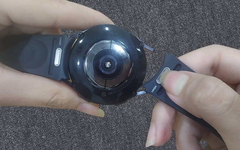 Bấm và giữ nút kim loại trên dây đồng hồ để thay dây đồng hồ